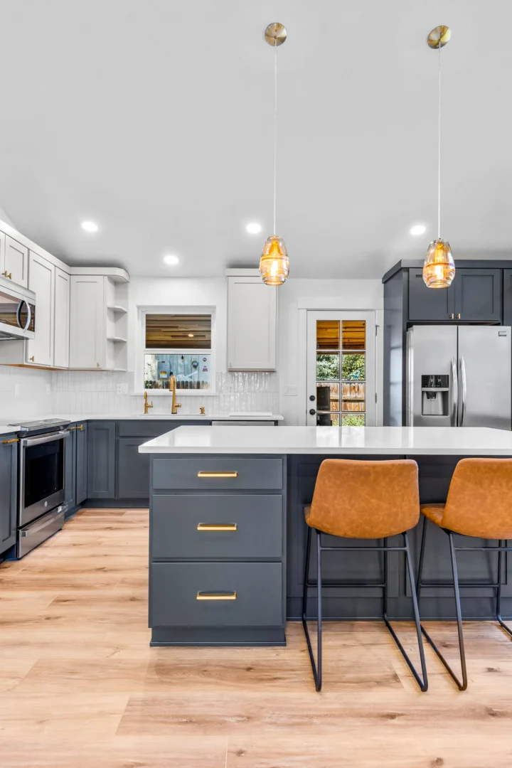 Flagstaff kitchen remodel with gray island, gold hardware, two-tone cabinets, and amber pendant lighting by Barden Home Builders