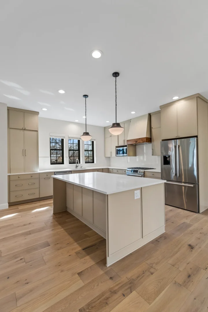 Kitchen remodel in Flagstaff AZ featuring large quartz island, greige shaker cabinets, and hardwood floors by Barden Home Builders